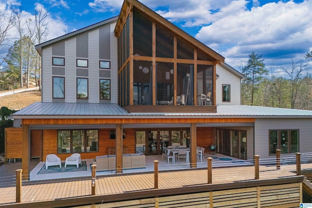 back of property with metal roof, outdoor lounge area, and a sunroom