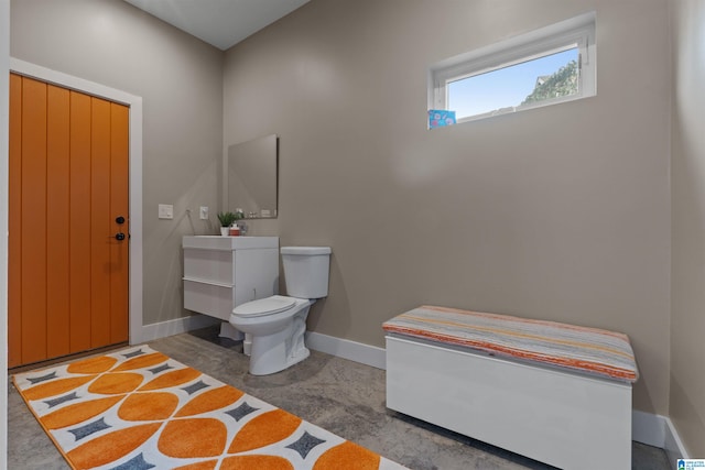 bathroom featuring vanity, toilet, concrete flooring, and baseboards