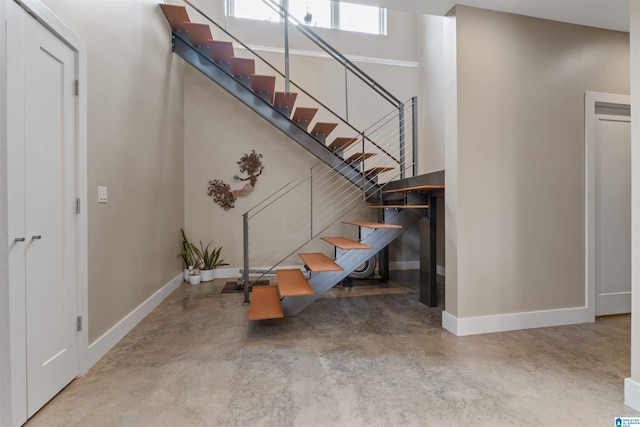 staircase with baseboards and concrete flooring