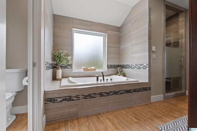 bathroom featuring a stall shower, toilet, a bath, and vaulted ceiling