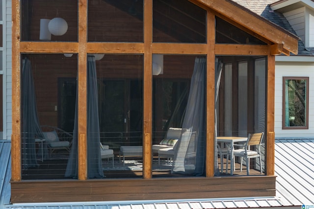 exterior space with a shingled roof and a sunroom