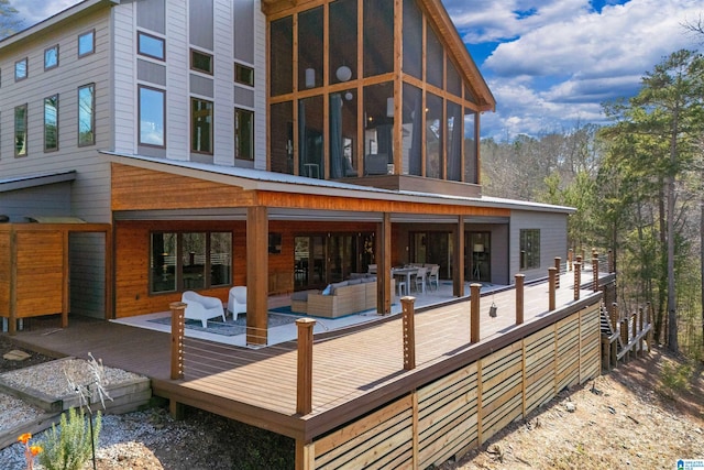 rear view of property with an outdoor living space, a deck, and a sunroom