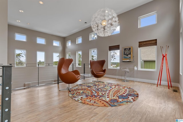 sitting room with visible vents, baseboards, wood finished floors, and a towering ceiling