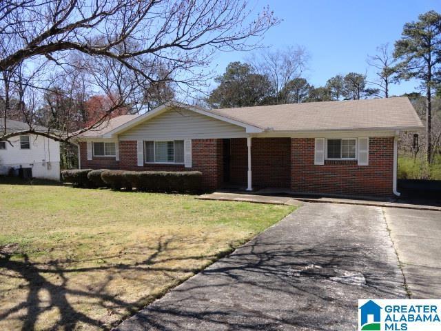 ranch-style home featuring a front yard, brick siding, and driveway