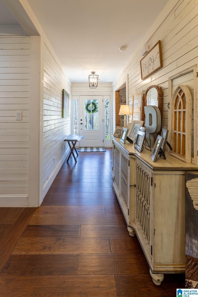 hall with baseboards, wood walls, and wood-type flooring