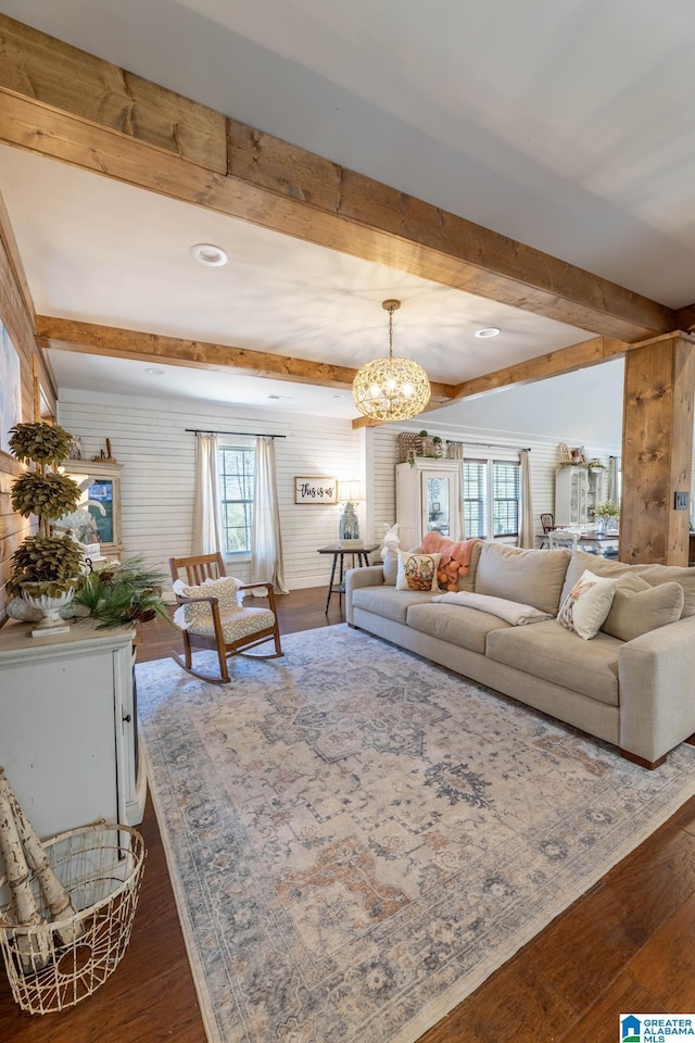 living room with beam ceiling, wood finished floors, and a chandelier