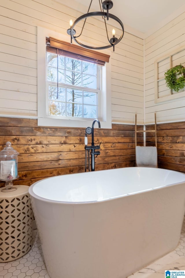 full bathroom featuring a freestanding tub, wooden walls, an inviting chandelier, and tile patterned flooring