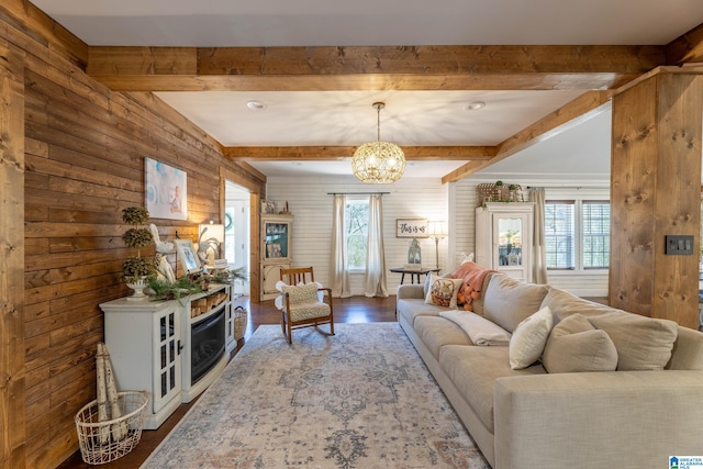 living room with a notable chandelier, beamed ceiling, and wood finished floors