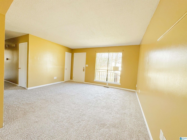 empty room with visible vents, baseboards, a textured ceiling, and carpet flooring