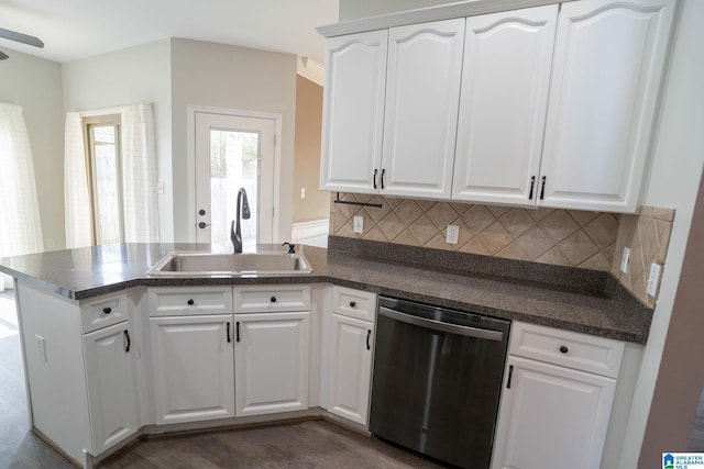 kitchen with dark countertops, a sink, a peninsula, and stainless steel dishwasher