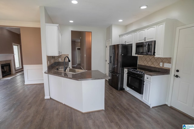 kitchen featuring dark wood-style floors, stainless steel fridge with ice dispenser, a sink, black range with electric cooktop, and dark countertops