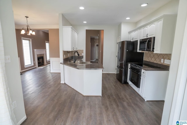 kitchen featuring a sink, stainless steel microwave, dark countertops, black range with electric cooktop, and white cabinetry