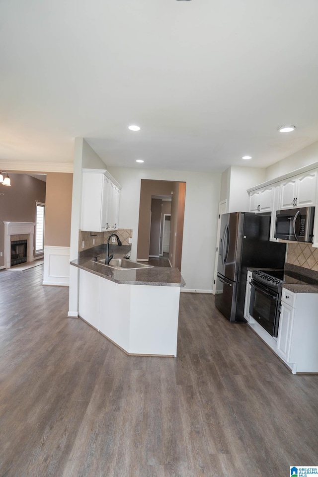 kitchen with dark countertops, white cabinetry, and black range with electric cooktop