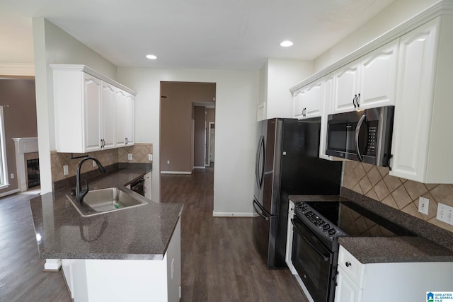 kitchen with stainless steel microwave, a fireplace, a peninsula, black electric range oven, and a sink