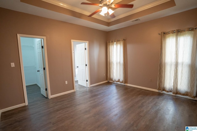 spare room featuring a raised ceiling, baseboards, dark wood-type flooring, and ornamental molding