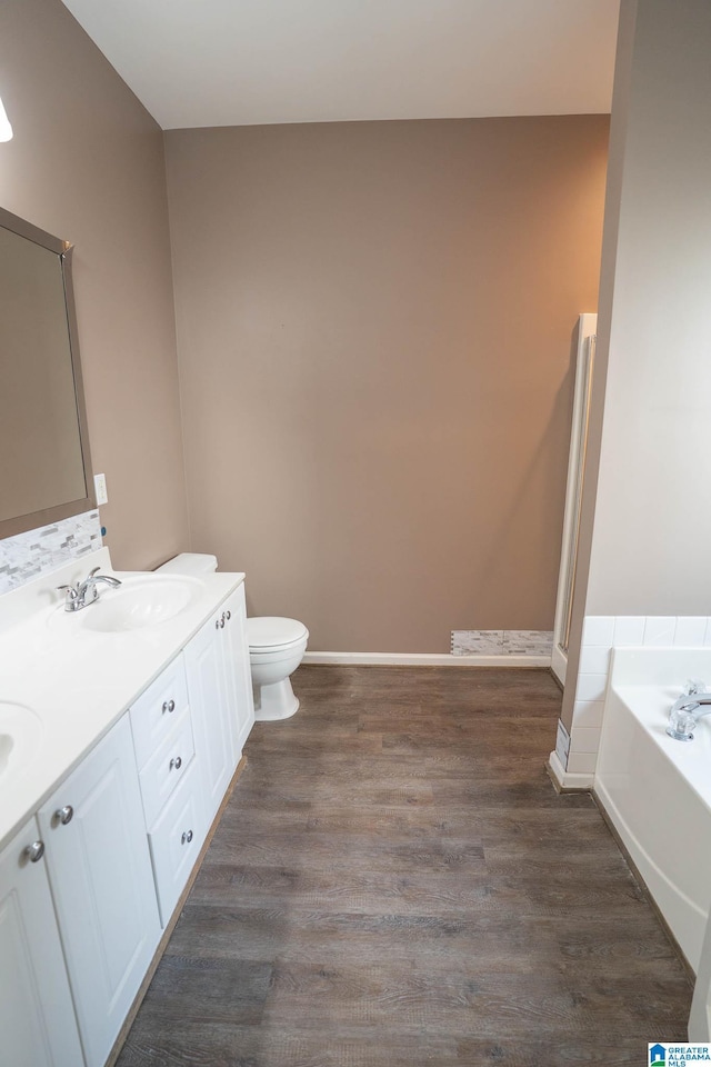 bathroom featuring a sink, a garden tub, wood finished floors, and double vanity