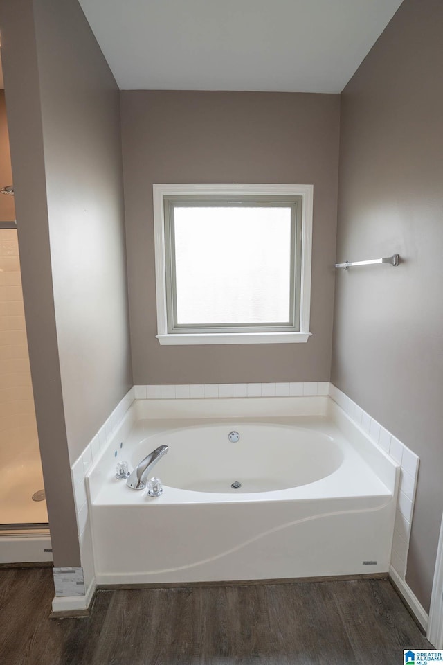 bathroom featuring baseboard heating, a shower stall, a garden tub, and wood finished floors