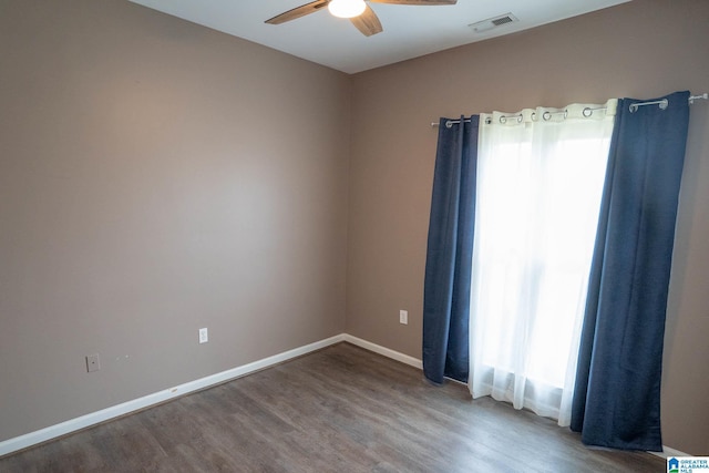 spare room featuring ceiling fan, wood finished floors, visible vents, and baseboards