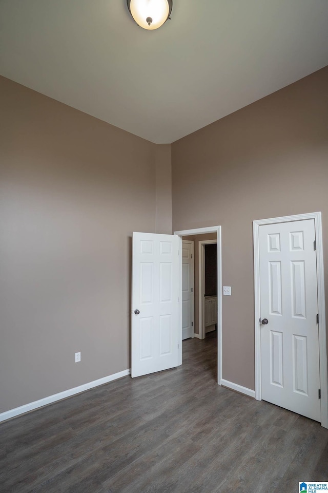 unfurnished bedroom with dark wood-type flooring and baseboards