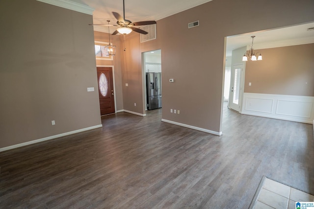 interior space featuring dark wood-style floors, visible vents, ornamental molding, a decorative wall, and ceiling fan with notable chandelier