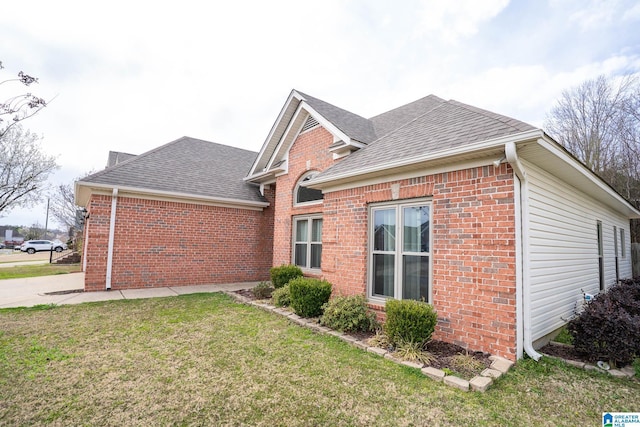 view of home's exterior featuring a yard, brick siding, and roof with shingles