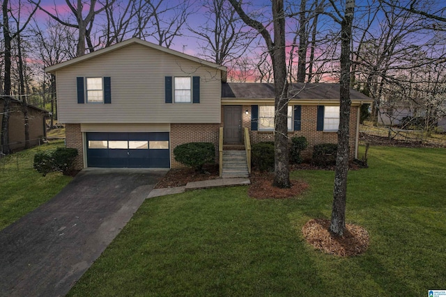 tri-level home featuring a front lawn, a garage, brick siding, and driveway