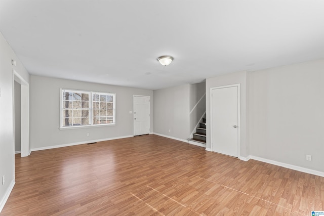 interior space with stairs, visible vents, baseboards, and light wood finished floors