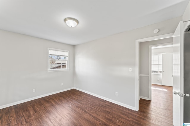 empty room with dark wood finished floors and baseboards