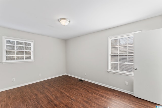 unfurnished room featuring visible vents, baseboards, and wood finished floors