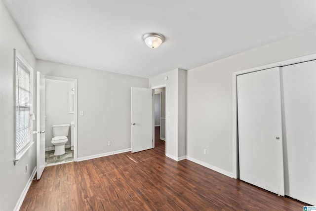 unfurnished bedroom featuring connected bathroom, dark wood-style floors, a closet, and baseboards