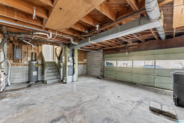 garage featuring electric panel, heating unit, and electric water heater