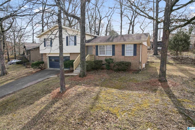 split level home featuring aphalt driveway, an attached garage, and brick siding