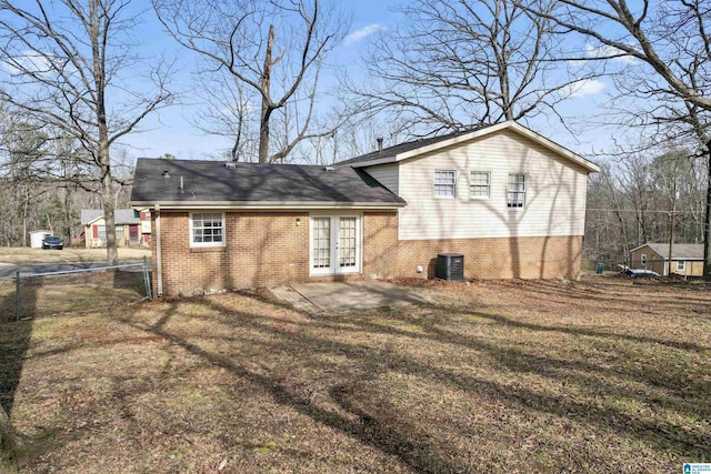 rear view of property with central air condition unit, fence, french doors, brick siding, and a patio area