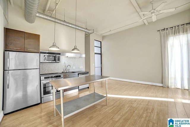 kitchen with light wood-style floors, tasteful backsplash, appliances with stainless steel finishes, and a sink