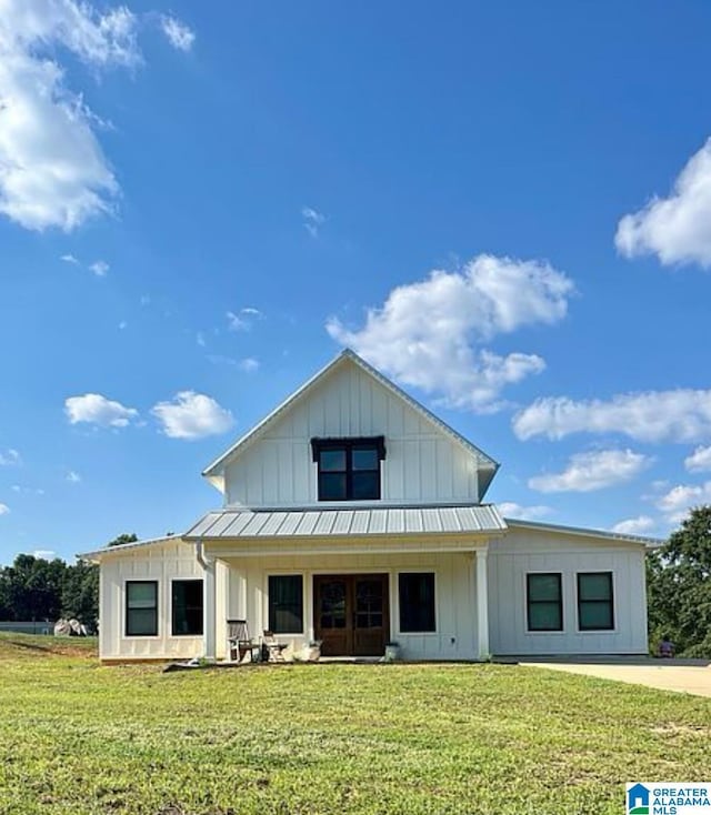 view of front of home featuring a standing seam roof, board and batten siding, driveway, and a front lawn