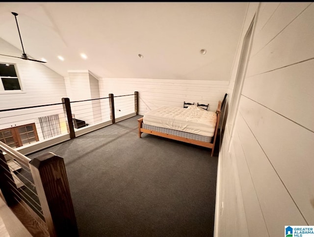 bedroom with vaulted ceiling, wooden walls, and carpet