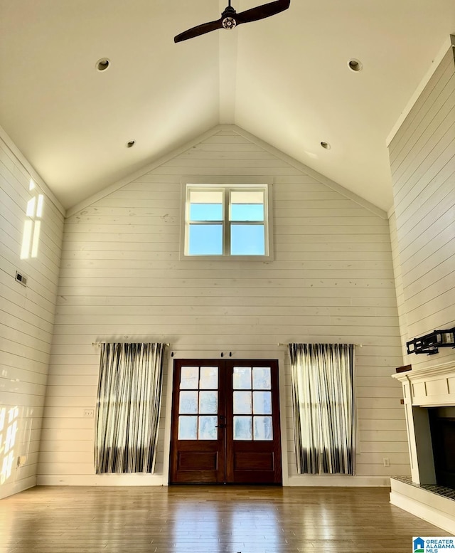 unfurnished living room featuring french doors, high vaulted ceiling, a ceiling fan, and wood finished floors