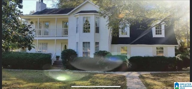 view of front of home with a balcony and a chimney