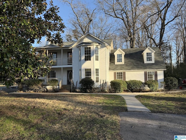 traditional-style house featuring a front lawn and a balcony