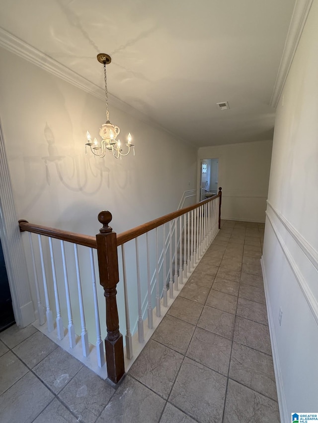 stairway featuring visible vents, a decorative wall, ornamental molding, and a chandelier