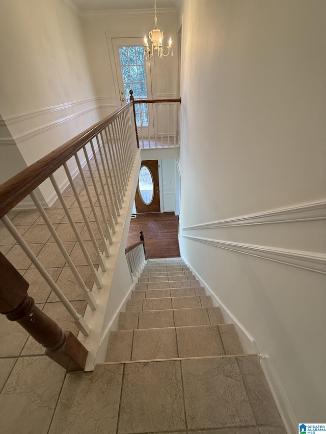 staircase with crown molding, baseboards, and a chandelier