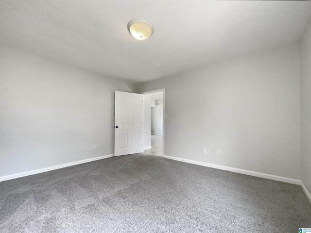 unfurnished room featuring dark colored carpet and baseboards