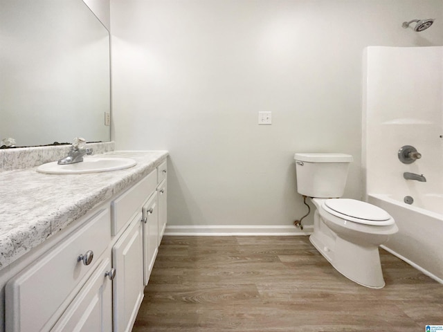 bathroom featuring tub / shower combination, baseboards, toilet, wood finished floors, and vanity