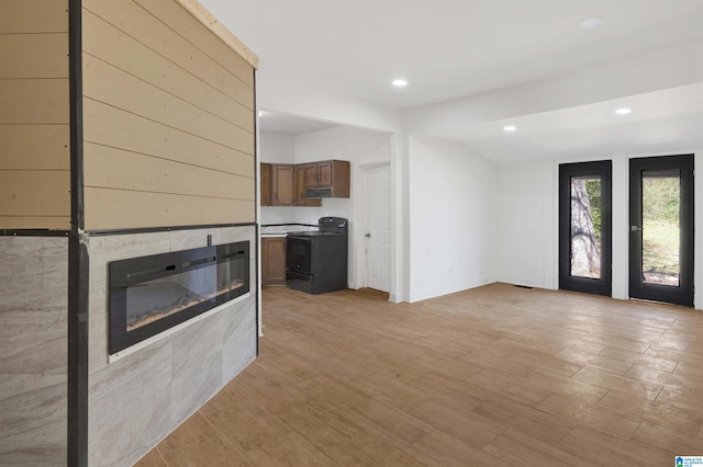 unfurnished living room with light wood finished floors, a glass covered fireplace, and recessed lighting