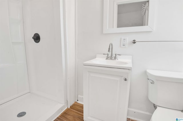 bathroom with wood finished floors, toilet, a stall shower, and vanity