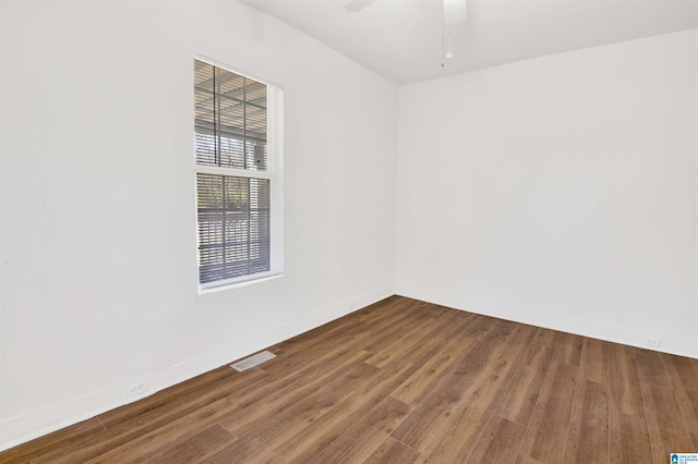 spare room with ceiling fan, visible vents, baseboards, and wood finished floors