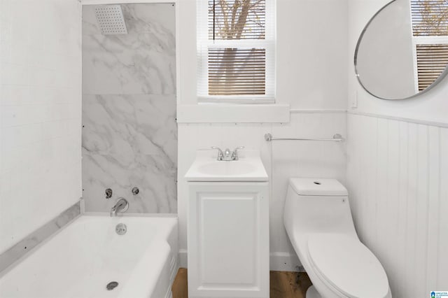 bathroom with a bathtub, a wainscoted wall, plenty of natural light, and toilet