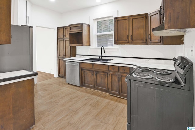 kitchen with light wood-style flooring, a sink, under cabinet range hood, appliances with stainless steel finishes, and light countertops