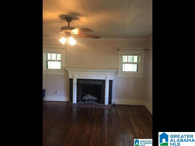 unfurnished living room with ornamental molding, a ceiling fan, wood finished floors, baseboards, and a tile fireplace