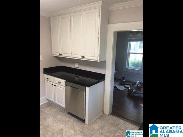 kitchen featuring dishwasher, dark countertops, white cabinetry, and ornamental molding